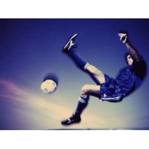  Soccer Player Jumping in Mid Air to Kick a Soccer Ball 