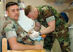 Hospital Corpsman draws blood from a patient as part of his duties 