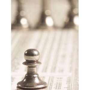 Silver Pawn on Newspaper Stock Market Report with Line of Chess Pieces 